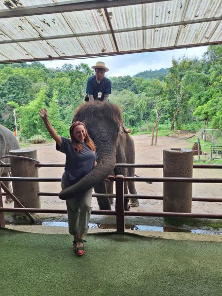 A guest waving happily as an elephant reaches its trunk toward her - lifeonwheel.com