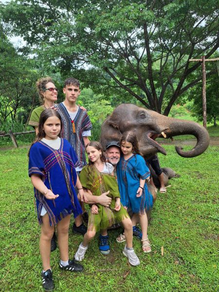 The family group smiling next to an elephant with mouth open - lifeonwheel.com