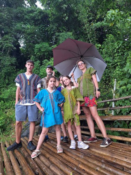 A family with umbrellas posing on a bamboo raft in the rain - lifeonwheel.com