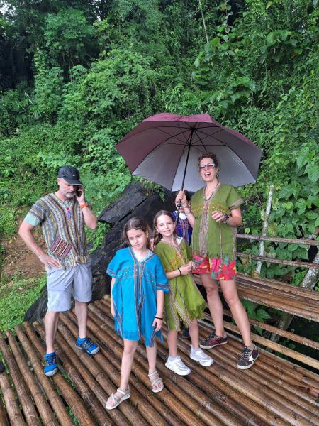 The family under a shared umbrella on a bamboo bridge in the rain - lifeonwheel.com