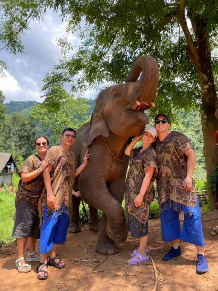 A group in matching elephant-print outfits with an elephant raising its trunk - lifeonwheel.com