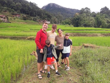 A family beside the young rice with the hills behind - lifeonwheel.com
