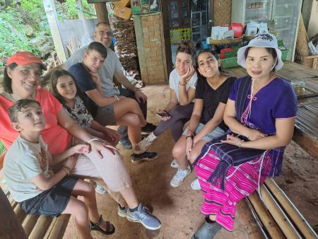 A family and hill tribe host resting together at a village home - lifeonwheel.com