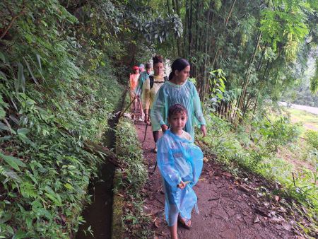Trekkers in rain ponchos walking a jungle trail single file - lifeonwheel.com