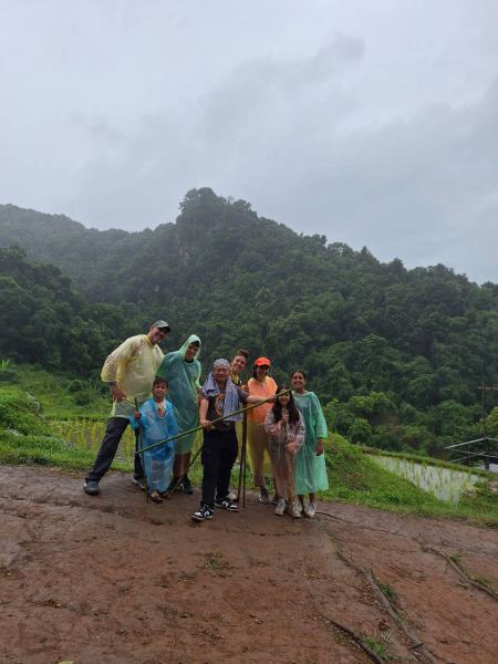 The trekking group posing with a forested mountain backdrop in the rain - lifeonwheel.com