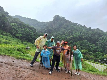 Trekkers posing on a muddy trail overlooking green rice terraces - lifeonwheel.com