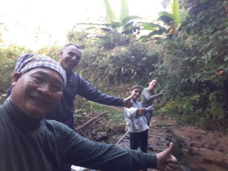 A guide with trekkers giving thumbs up beside a small forest stream - lifeonwheel.com