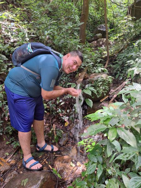 A trekker rinsing his hands at a small forest waterfall - lifeonwheel.com