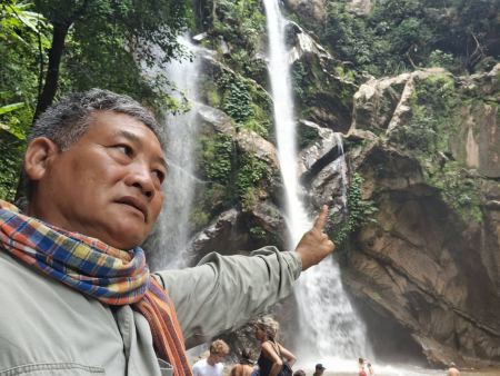 Our guide pointing up at the twin waterfall streams - lifeonwheel.com
